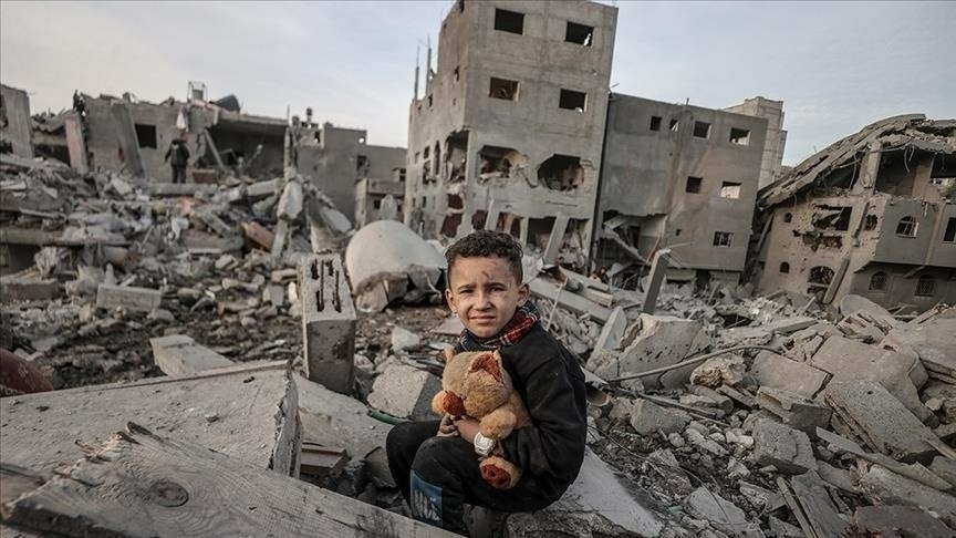 Child with toy sitting in rubble